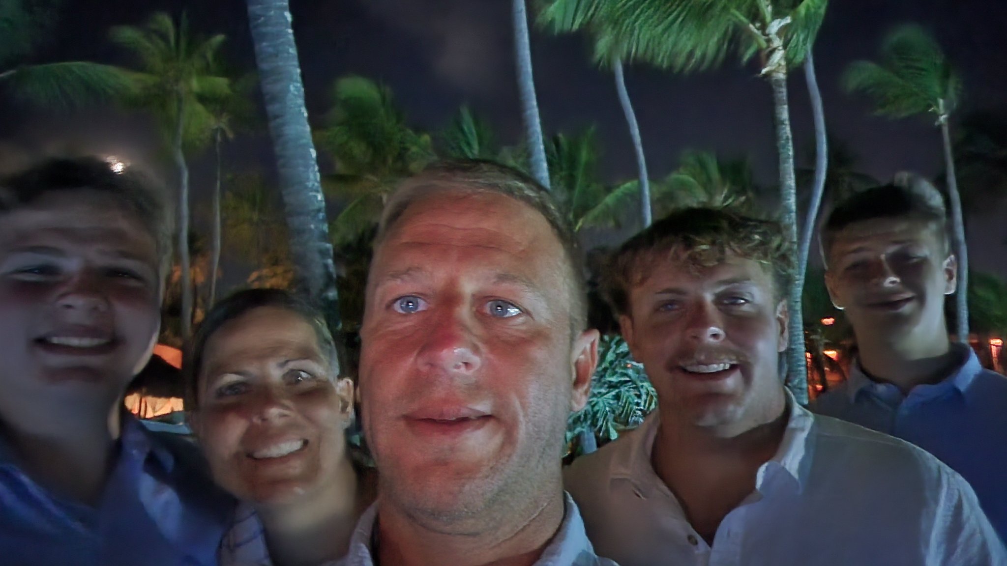 The whole group smiling by the resort pool at dusk